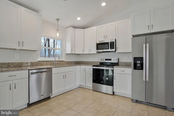 a kitchen with granite countertop white cabinets and stainless steel appliances