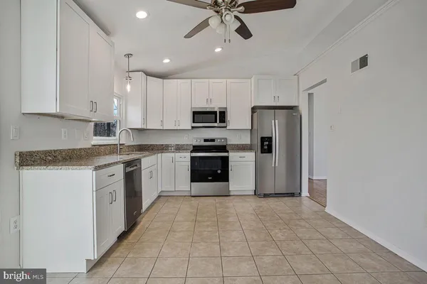 a kitchen with granite countertop a refrigerator stove top oven and sink