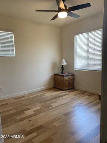 a view of empty room with wooden floor and fan
