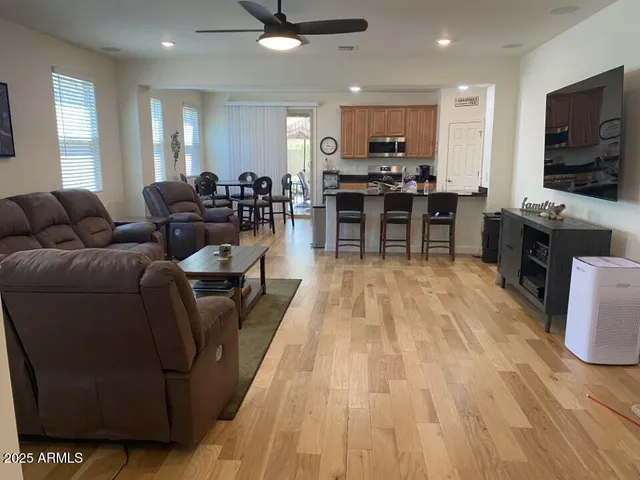 a living room with stainless steel appliances furniture wooden floor and a view of kitchen