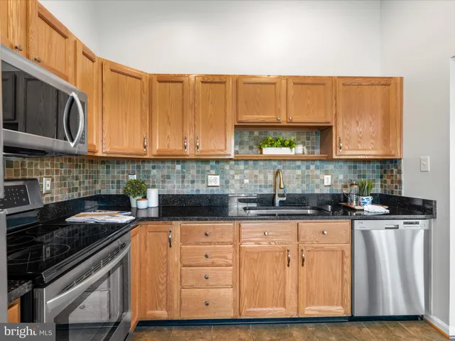 a kitchen with granite countertop a stove a sink dishwasher and cabinets with wooden floor