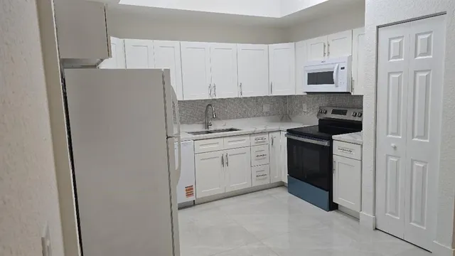 a kitchen with stainless steel appliances white cabinets and a refrigerator