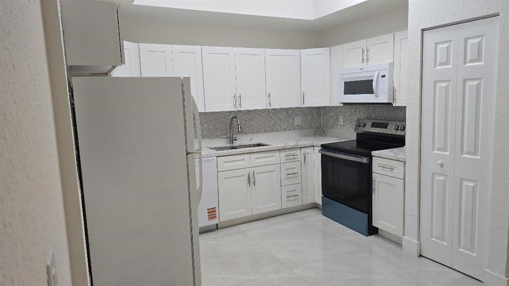 2801 Riverside Drive, Unit 104 Coral Springs, FL 33065 - Photo 3 of 22 a kitchen with white cabinets and white appliances