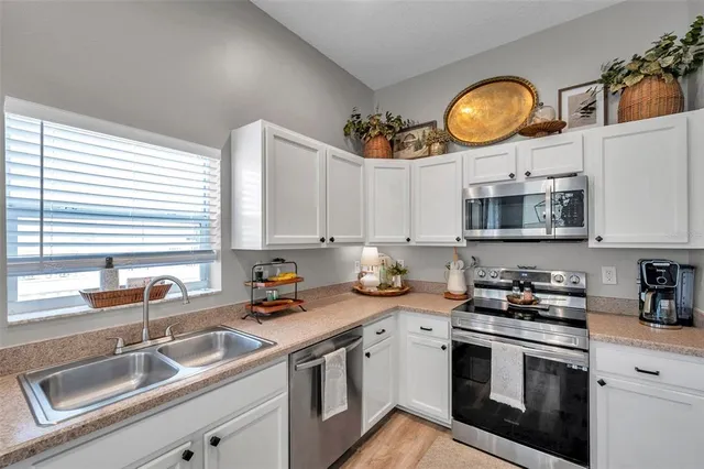 a kitchen with stainless steel appliances granite countertop a sink a stove and a wooden cabinets