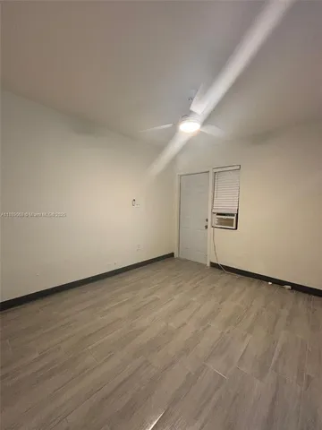 an empty room with wooden floor cabinet and windows