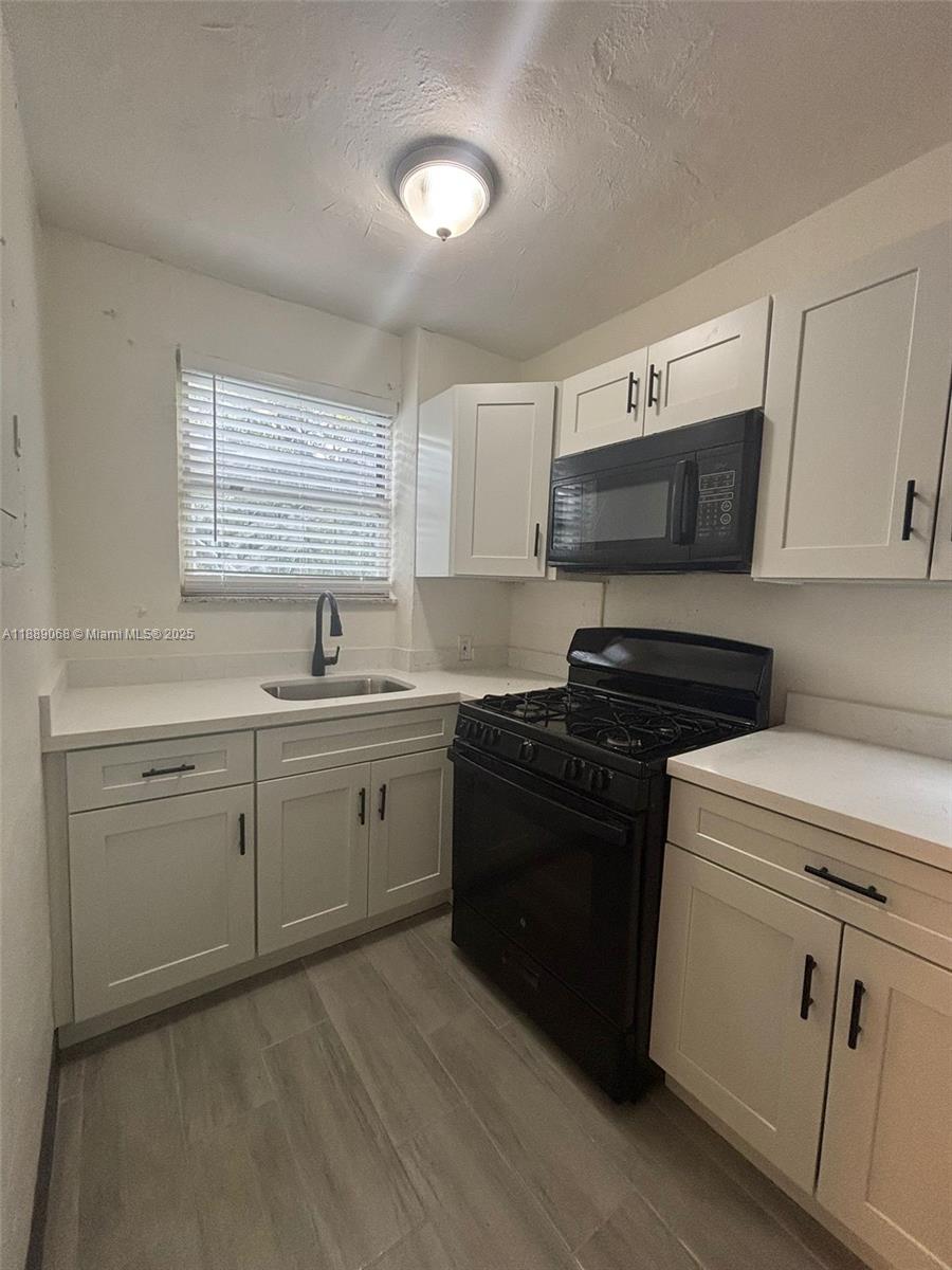 708 Northwest 4th Avenue, Unit 4 Miami, FL 33136 - Photo 7 of 17 a kitchen with cabinets appliances a sink and a window