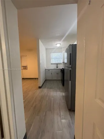 a view of a kitchen with a sink refrigerator and wooden floor