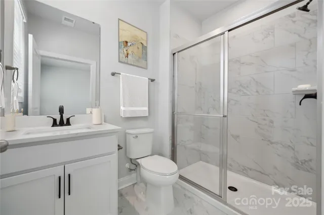 a bathroom with a shower sink vanity mirror and toilet