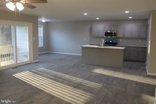 a living room with stainless steel appliances furniture a window and a kitchen