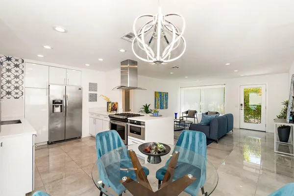 a living room with stainless steel appliances furniture a rug and a chandelier