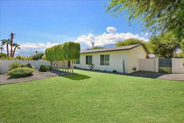 a view of a house with backyard and a tree