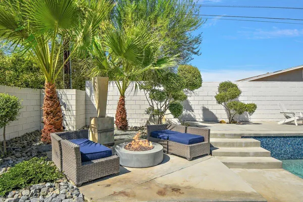 a view of a backyard with table and chairs potted plants and large tree