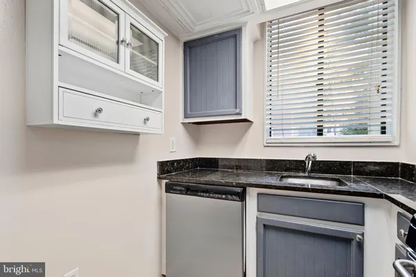 a kitchen with granite countertop white cabinets and black appliances