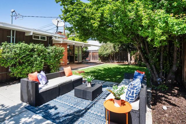 a view of a patio with couches table and chairs potted plants and large tree