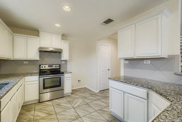 a kitchen with granite countertop white cabinets stainless steel appliances and sink