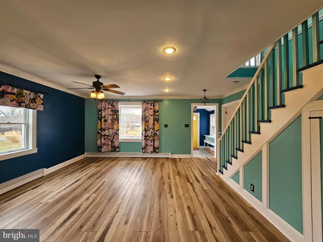 a view of an empty room with wooden floor a ceiling fan and window