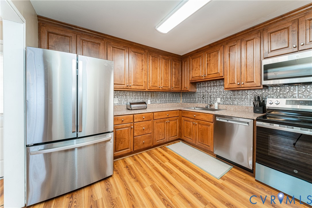 26746 Oxford Road Ruther Glen, VA 22546 - Photo 10 of 25 a kitchen with white cabinets stainless steel appliances and wooden floor