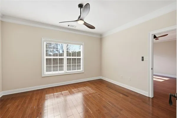 an empty room with wooden floor ceiling fan and windows
