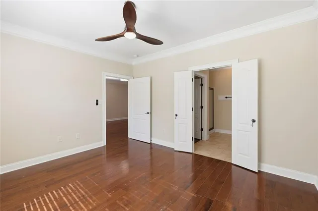 an empty room with wooden floor ceiling fan and windows