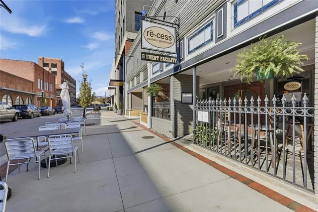 a dining hall with stainless steel appliances granite countertop a stove a refrigerator a dining table and chairs with wooden floor