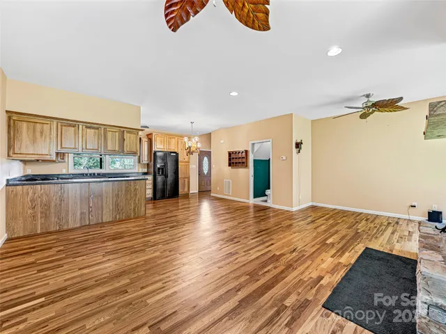 a kitchen with stainless steel appliances granite countertop a refrigerator a sink dishwasher a stove and a dining table with wooden floor