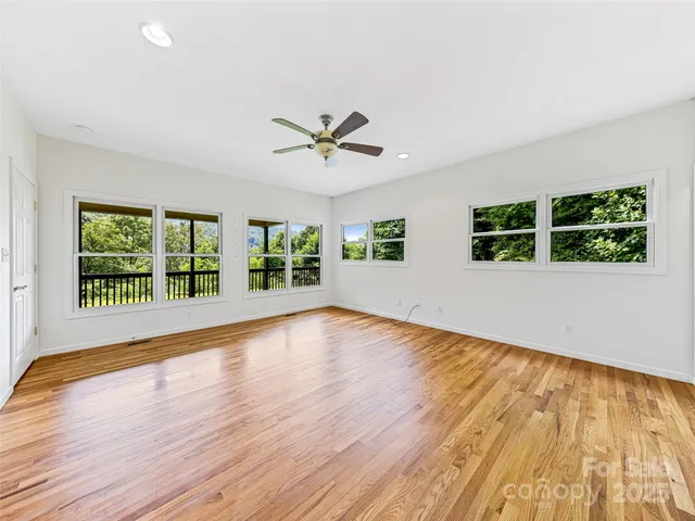 a view of an empty room with a window and wooden floor