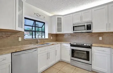 a kitchen with granite countertop white cabinets white stainless steel appliances and a sink
