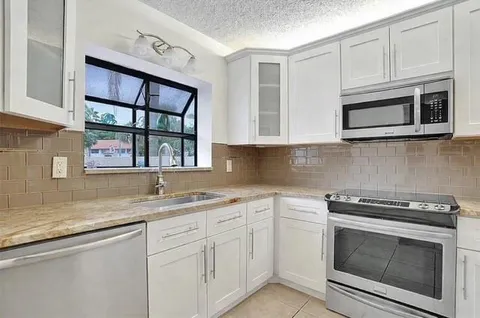 a kitchen with stainless steel appliances granite countertop white cabinets a sink and dishwasher