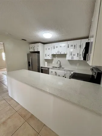 a large white kitchen with kitchen island stainless steel appliances sink and cabinets