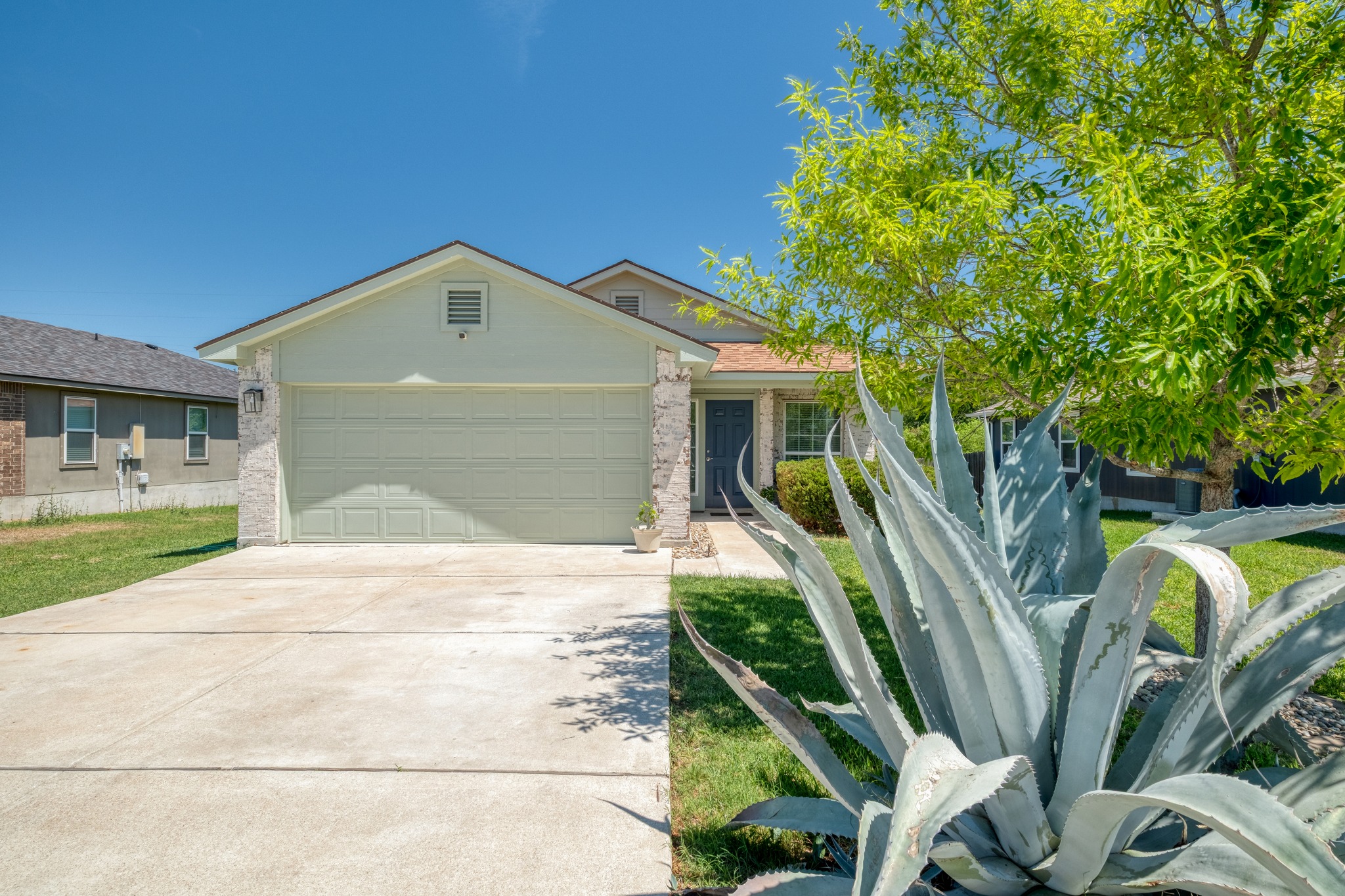 Ranch-style house with an attached garage, driveway, and brick siding