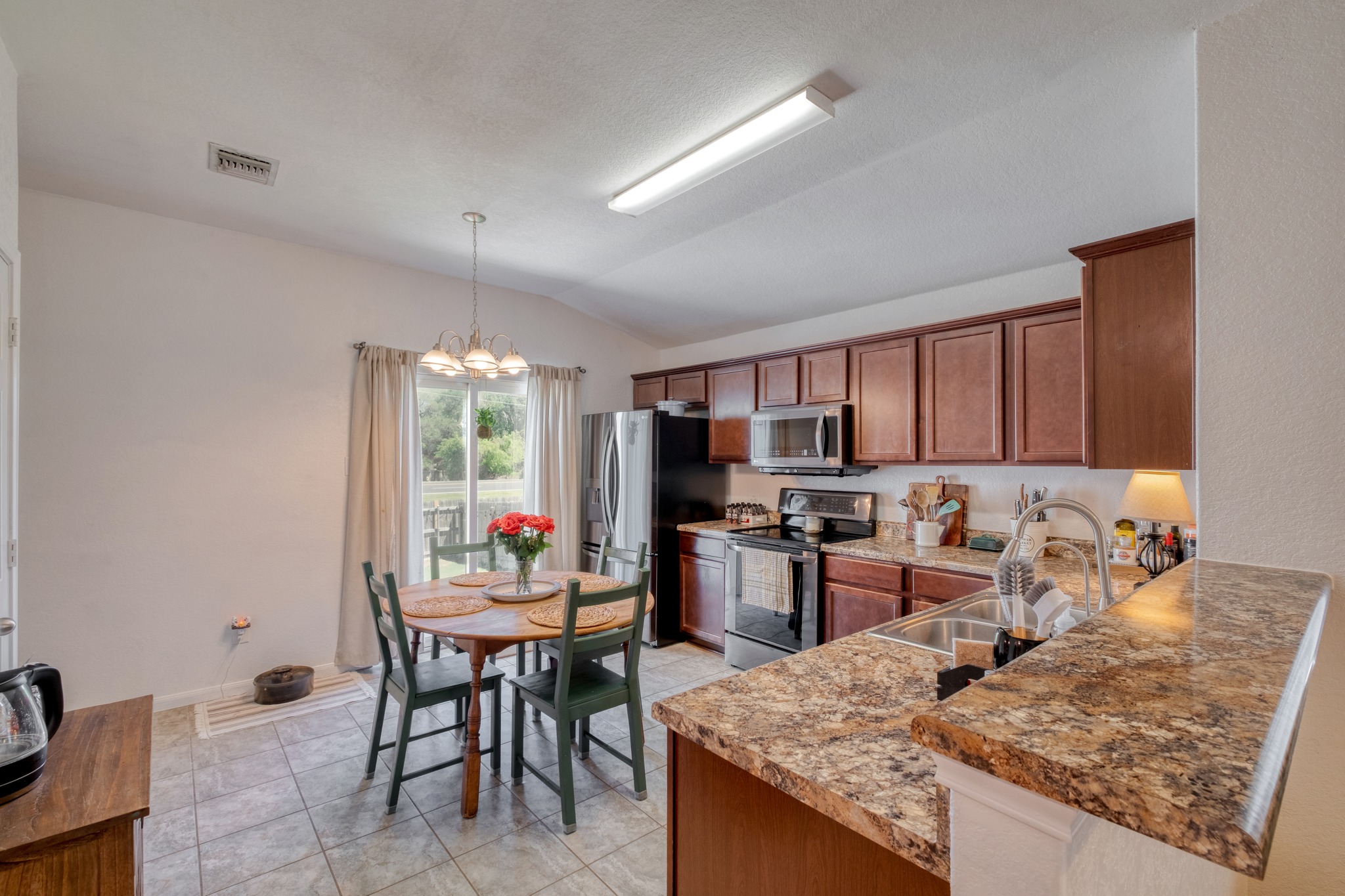 174 Falcon Drive Luling, TX 78648 - Photo 11 of 38 Kitchen with stainless steel appliances, a peninsula, wood finish cabinets, suspended lighting, and vaulted ceiling