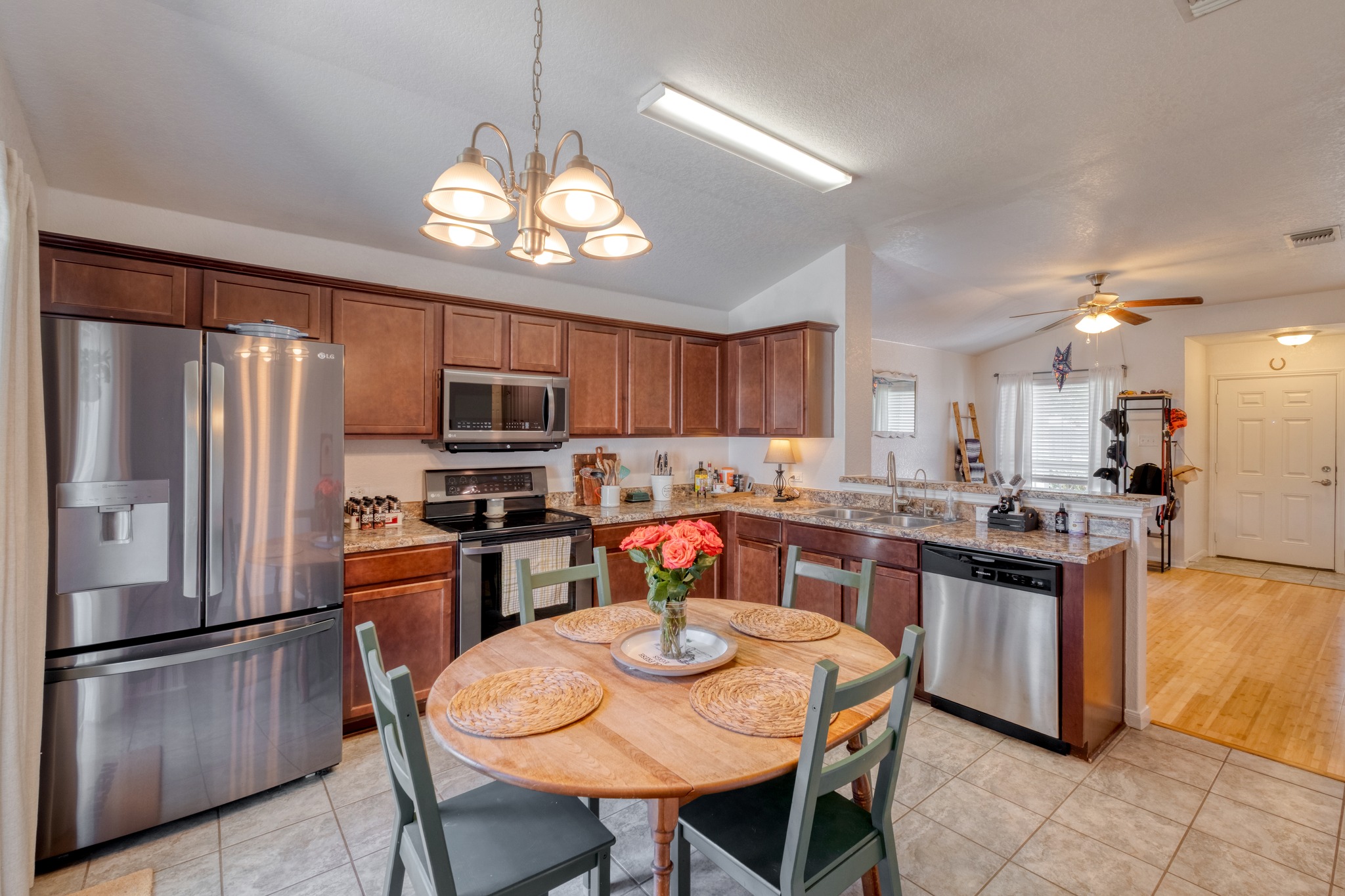 174 Falcon Drive Luling, TX 78648 - Photo 12 of 38 Kitchen featuring stainless steel appliances, vaulted ceiling, a peninsula, light tile patterned floors, and light stone counters
