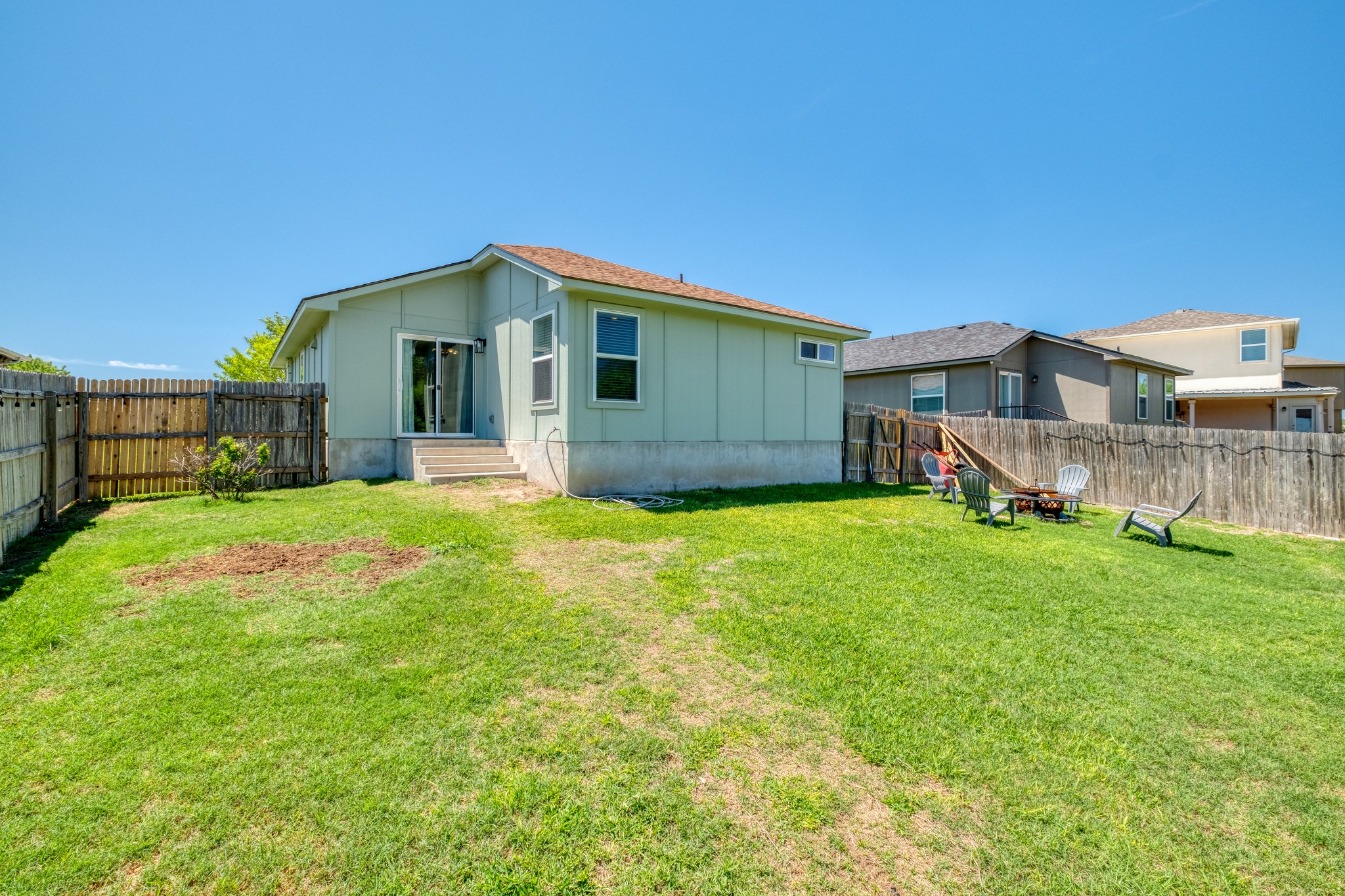 174 Falcon Drive Luling, TX 78648 - Photo 23 of 38 Rear view of house with a fenced backyard, board and batten siding, and entry steps