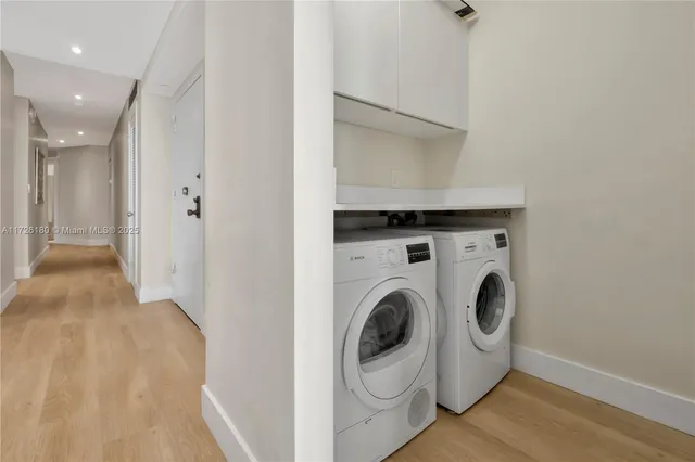 a view of washer and dryer with bathroom in the background