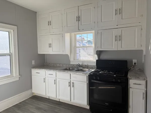 a kitchen with granite countertop white cabinets and black appliances