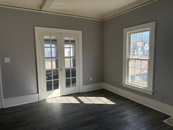 an empty room with wooden floor and windows