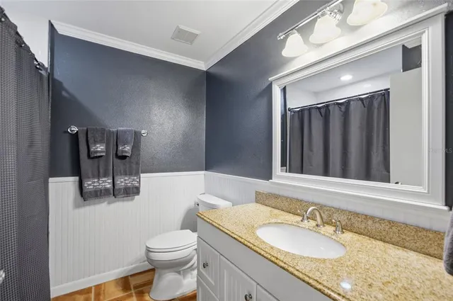a bathroom with a granite countertop sink toilet and mirror
