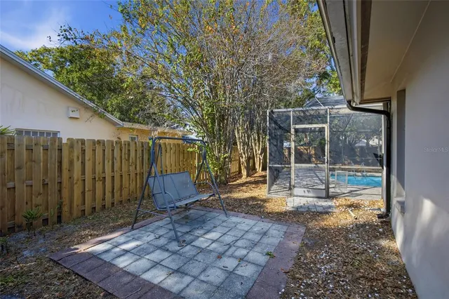a view of a backyard with large trees and wooden fence