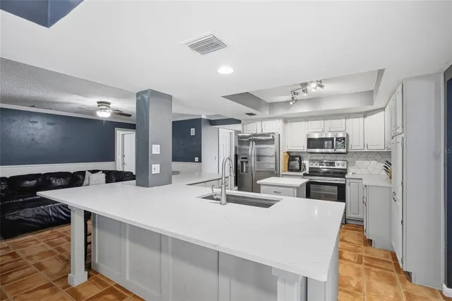 a kitchen with stainless steel appliances kitchen island granite countertop a sink stove and refrigerator