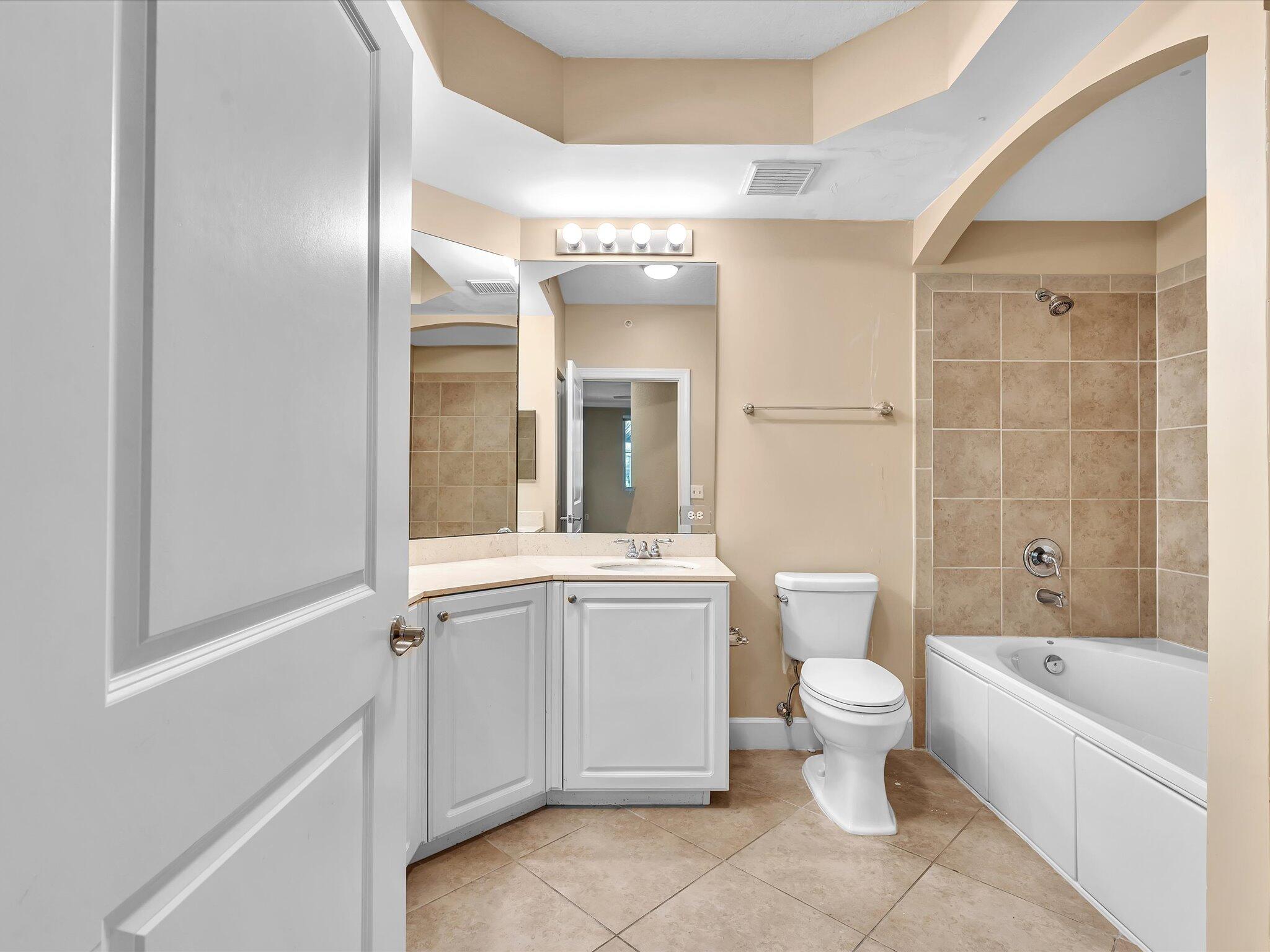 4303 Renaissance Way, Unit 303 Boynton Beach, FL 33426 - Photo 49 of 74 a bathroom with a granite countertop toilet a sink and bathtub