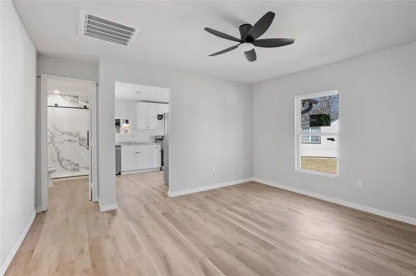 a view of empty room with wooden floor and ceiling fan