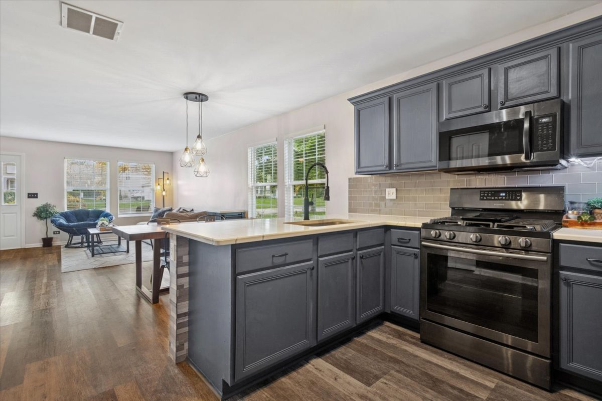 60 Wingate Drive, Unit 60 Oswego, IL 60543 - Photo 9 of 23 a kitchen with stainless steel appliances granite countertop a stove top oven a sink dishwasher a dining table and chairs with wooden floor