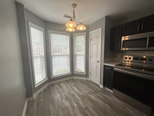 a view of an empty room with a kitchen and a window