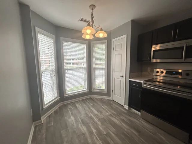 a view of an empty room with a kitchen and a window