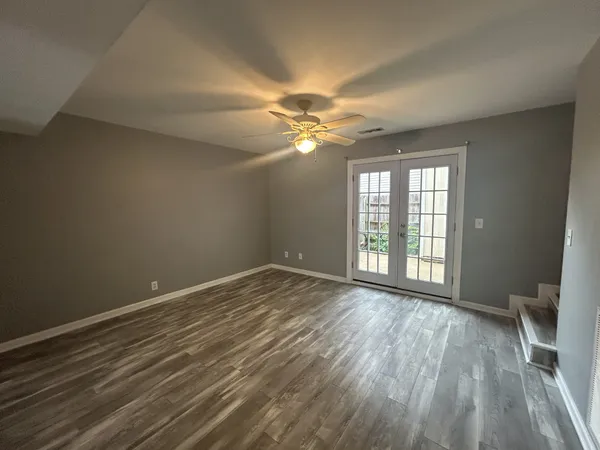 a view of an empty room with a window and wooden floor
