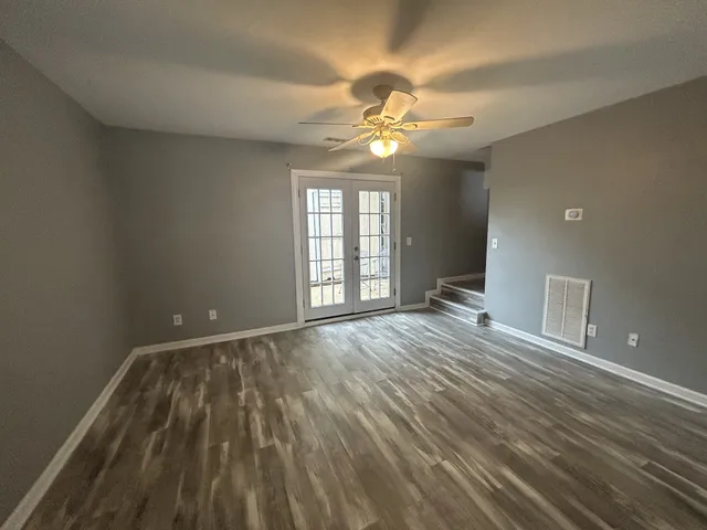 a view of an empty room with a window and wooden floor