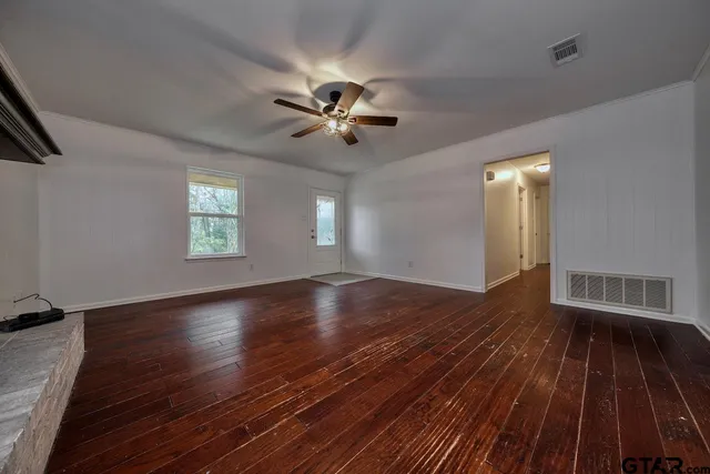 a view of an empty room with wooden floor and a fireplace