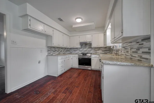 a kitchen with granite countertop wooden floors stainless steel appliances and sink