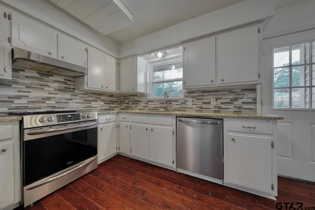 a kitchen with granite countertop cabinets stainless steel appliances and wooden floor