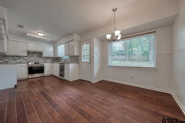 a view of a kitchen with wooden floor a sink a refrigerator and window